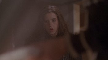 A young girl is looking into a mirror