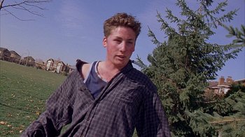 A man in a plaid shirt standing next to a tree