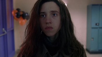 A young woman with long hair stares into the camera