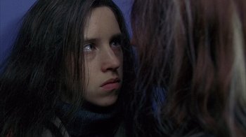 A young woman looking into a mirror while standing next to another woman