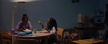Movie still from “Girlhood” (2014), directed by Céline Sciamma – A woman sitting at a table eating food; Medium shot, Over the shoulder angle