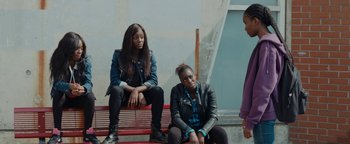 Movie still from “Girlhood” (2014), directed by Céline Sciamma – A group of people sitting on top of a red bench; Medium shot, High angle