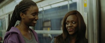 Movie still from “Girlhood” (2014), directed by Céline Sciamma – Two women are talking and smiling on a bus; Close Up shot, Over the shoulder angle
