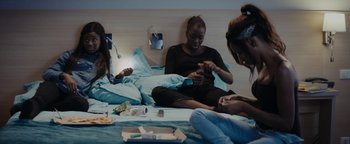 Movie still from “Girlhood” (2014), directed by Céline Sciamma – A group of people sitting on a bed; Medium shot, High angle