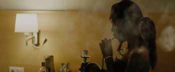 Movie still from “Girlhood” (2014), directed by Céline Sciamma – A woman is smoking a hookah in a room; Medium shot, Over the shoulder angle