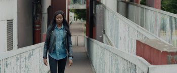 Movie still from “Girlhood” (2014), directed by Céline Sciamma – A woman walking down the street in a leather jacket; Medium shot, Over the shoulder angle