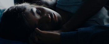 Movie still from “Girlhood” (2014), directed by Céline Sciamma – A woman laying down in the dark with her head resting on her hand; Close Up shot, High angle