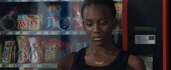 Movie still from “Girlhood” (2014), directed by Céline Sciamma – A young woman wearing a black tank top and a gold necklace; Close Up shot, Over the shoulder angle
