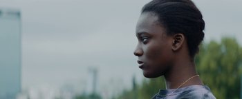 Movie still from “Girlhood” (2014), directed by Céline Sciamma – A person's face with trees in the background; Close Up shot, Low angle