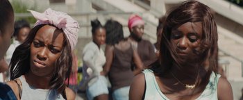 Movie still from “Girlhood” (2014), directed by Céline Sciamma – A group of people sitting on steps in front of a building; Close Up shot, Over the shoulder angle