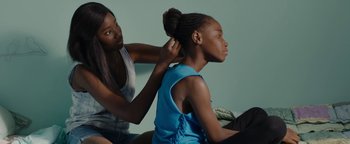 Movie still from “Girlhood” (2014), directed by Céline Sciamma – A young girl getting her hair combed by an adult; Medium shot, Over the shoulder angle