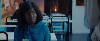 Movie still from “Girlhood” (2014), directed by Céline Sciamma – A young girl in a blue hoodie sitting in front of a table; Close Up shot, Over the shoulder angle