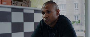Movie still from “Girlhood” (2014), directed by Céline Sciamma – A man sitting in front of a window; Close Up shot, Low angle