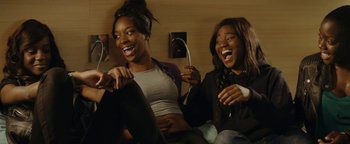 Movie still from “Girlhood” (2014), directed by Céline Sciamma – Two young women sitting next to each other on a couch; Medium shot, High angle