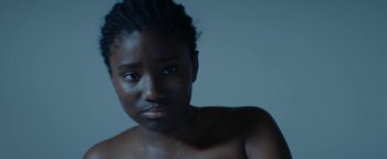 Movie still from “Girlhood” (2014), directed by Céline Sciamma – A young woman with a bare chest is looking at the camera; Close Up shot, High angle