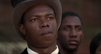 Movie still from “Glory” (1989), directed by Edward Zwick – A man wearing a hat is looking at the camera with another man; Close Up shot, Over the shoulder angle