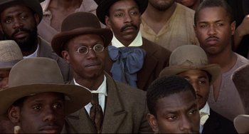 Movie still from “Glory” (1989), directed by Edward Zwick – A group of men in suits and hats sitting in a crowd; Close Up shot, High angle