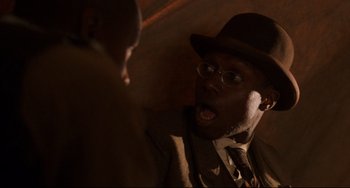 Movie still from “Glory” (1989), directed by Edward Zwick – A man in a suit and a hat talking to another man in a suit; Close Up shot, Over the shoulder angle