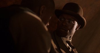 Movie still from “Glory” (1989), directed by Edward Zwick – A man wearing a suit and hat talking to another man in a suit; Close Up shot, Over the shoulder angle