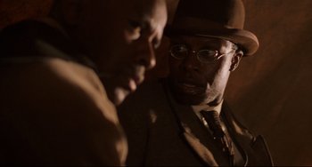 Movie still from “Glory” (1989), directed by Edward Zwick – A man in a suit and hat talking to another man in a suit; Close Up shot, Over the shoulder angle