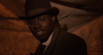Movie still from “Glory” (1989), directed by Edward Zwick – A man in a suit and a hat is posing for a picture; Close Up shot, Low angle