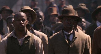 Movie still from “Glory” (1989), directed by Edward Zwick – A group of men in suits and hats are standing together; Medium shot, Over the shoulder angle