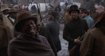 Movie still from “Glory” (1989), directed by Edward Zwick – A group of men in hats and coats standing next to each other; Medium shot, Over the shoulder angle