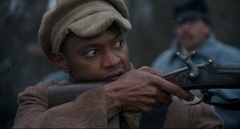 Movie still from “Glory” (1989), directed by Edward Zwick – A man holding a rifle while wearing a hat; Close Up shot, Over the shoulder angle