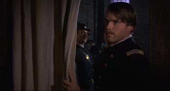 Movie still from “Glory” (1989), directed by Edward Zwick – A man standing next to a curtain in front of another man; Close Up shot, Over the shoulder angle