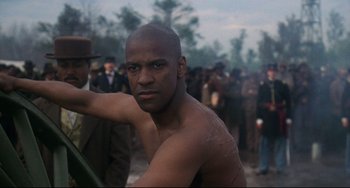 Movie still from “Glory” (1989), directed by Edward Zwick – A man with no shirt is standing in front of a group of people; Close Up shot, Low angle