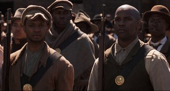 Movie still from “Glory” (1989), directed by Edward Zwick – A group of men standing next to each other holding guns; Medium shot, Over the shoulder angle