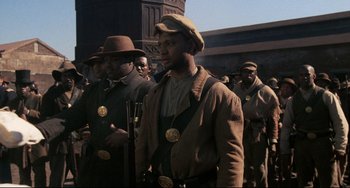 Movie still from “Glory” (1989), directed by Edward Zwick – A group of men standing next to each other on a street; Medium shot, Low angle