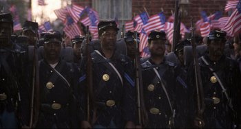Movie still from “Glory” (1989), directed by Edward Zwick – A group of men in uniforms are marching in a parade; Wide shot, High angle