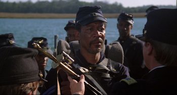 Movie still from “Glory” (1989), directed by Edward Zwick – A group of men standing next to a body of water; Close Up shot, Over the shoulder angle