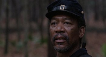 Movie still from “Glory” (1989), directed by Edward Zwick – An older man wearing a black hat in a wooded area; Close Up shot, Low angle