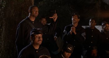 Movie still from “Glory” (1989), directed by Edward Zwick – A group of men in black uniforms are standing together; Medium shot, Low angle