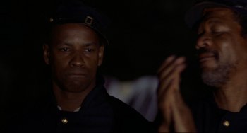 Movie still from “Glory” (1989), directed by Edward Zwick – A person clapping in the dark; Close Up shot, Over the shoulder angle