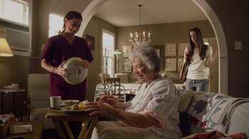 Movie still from “God's Not Dead” (2014), directed by Harold Cronk – An older woman sitting at a table with a plate of food; Medium shot, Over the shoulder angle
