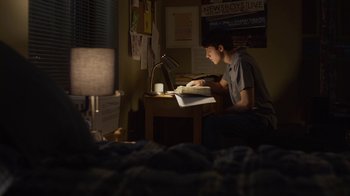 Movie still from “God's Not Dead” (2014), directed by Harold Cronk – A man sitting at a desk in the dark writing; Medium shot, High angle