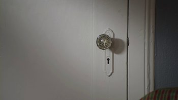 Movie still from “God's Not Dead” (2014), directed by Harold Cronk – A door knob on a white wall with a key hole; Extreme Close Up shot, High angle