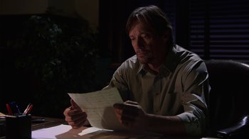 Movie still from “God's Not Dead” (2014), directed by Harold Cronk – A man sitting at a table looking at a piece of paper; Medium shot, Low angle