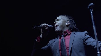 Movie still from “God's Not Dead” (2014), directed by Harold Cronk – A man with dreadlocks is singing into a microphone; Close Up shot, Low angle