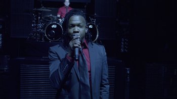 Movie still from “God's Not Dead” (2014), directed by Harold Cronk – A man in a suit is singing into a microphone; Medium shot, Low angle