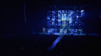 Movie still from “God's Not Dead” (2014), directed by Harold Cronk – A stage with a man playing a violin and a man standing on a stage with a microphone; Extreme Wide shot, High angle