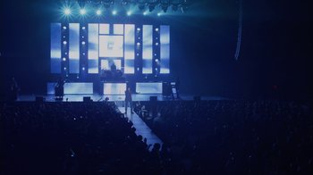 Movie still from “God's Not Dead” (2014), directed by Harold Cronk – A man standing on a stage in front of an audience; Extreme Wide shot, High angle