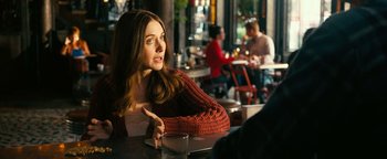 Movie still from “How to Be Single” (2016), directed by Christian Ditter – A beautiful young lady sitting at a table in a restaurant; Medium shot, Over the shoulder angle