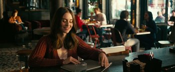 Movie still from “How to Be Single” (2016), directed by Christian Ditter – A woman sitting at a table with a glass of water; Medium shot, Over the shoulder angle