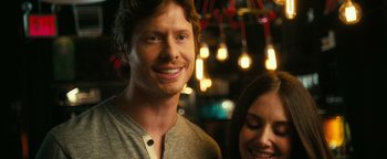 Movie still from “How to Be Single” (2016), directed by Christian Ditter – A man and a woman smile for the camera; Close Up shot, Over the shoulder angle
