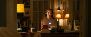 Movie still from “How to Be Single” (2016), directed by Christian Ditter – A woman sitting in front of an open laptop computer; Medium shot, Over the shoulder angle