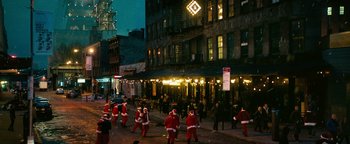 Movie still from “How to Be Single” (2016), directed by Christian Ditter – A group of people dressed as santa claus walk down the street; Extreme Wide shot, High angle